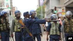 Police officers stand by as opposition party supporters gathered to hear a speech by the country's top opposition leader in Harare, Wednesday, Nov, 20, 2019. Zimbabwean police with riot gear fired tear gas and struck people who had gathered at the opposition party headquarters.