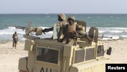 Peacekeepers from the African Union Mission in Somalia man weapons atop their Armored Personnel Carrier after capturing the former private Elmaan seaport from al-Shabaab insurgents, 30km (19 miles) east of Mogadishu, September 4, 2012. 