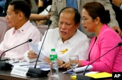 Former Philippine President Benigno Aquino III, center, confers with former Health Secretary Janet Garin as they both testify in a separate Lower House probe on the controversial anti-Dengue vaccine Dengvaxia, Feb. 26, 2018 in suburban Quezon city northeast of Manila, Philippines.