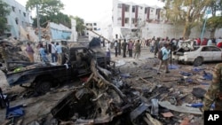 Rescue workers stand near the wreckage of vehicles in Mogadishu, Somalia, Oct 29, 2017, after a car bomb was detonated. 