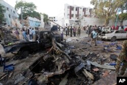 Rescue workers stand near the wreckage of vehicles in Mogadishu, Somalia, Oct 29, 2017, after a car bomb was detonated Saturday night.