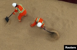 FILE - Employees working at cargo ship Kypros Land which is loading soybeans to China at Tiplam terminal in Santos, Brazil, March 13, 2017.