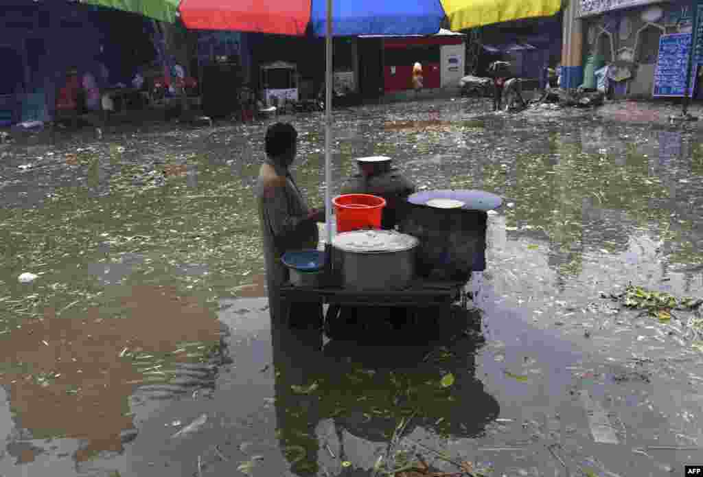 A food vendor waits for customers in a flooded area after heavy monsoon rains in Lahore, Pakistan.