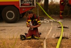 Seorang petugas pemadam kebakaran dari Slovakia mendinginkan diri saat terjadi kebakaran hutan di desa Avgaria di pulau Evia, sekitar 184 kilometer utara Athena, Yunani, Selasa, 10 Agustus 2021.