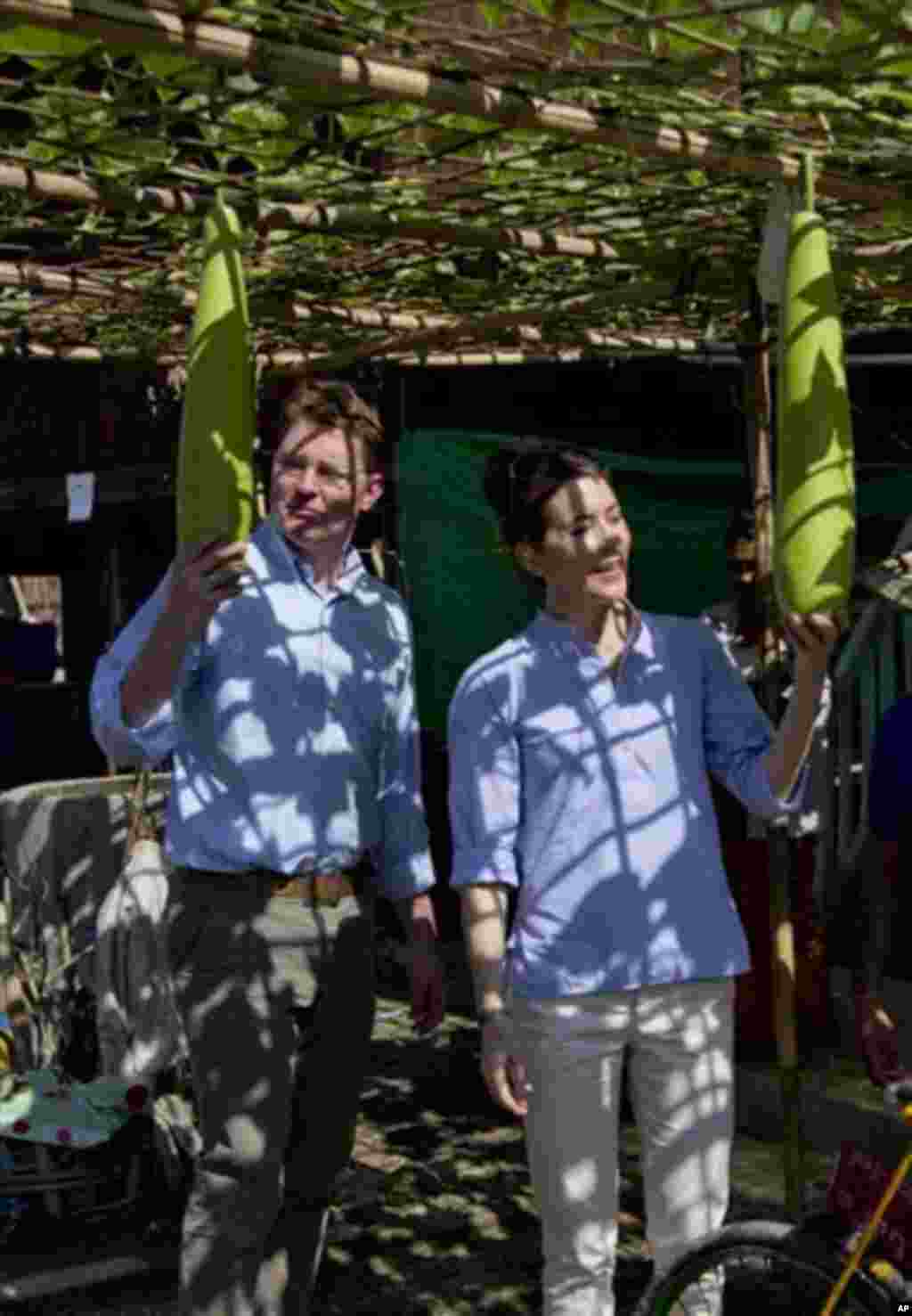 Denmark’s crown Princess Mary, right and Denmark’s Minister for Development Cooperation Rasmus Helveg Petersen, left, inspect vegetables during a visit to a Buddhist resettlement village in Sittwe, Rakhine State, Myanmar, Sunday, Jan. 12, 2014. Crown Prin