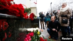 People pay tribute to passengers and crew members of Russian military Tu-154 plane crashed into the Black Sea, near a makeshift memorial outside the headquarters of the Alexandrov Ensemble, also known as the Red Army Choir, in Moscow, Dec. 25, 2016. 