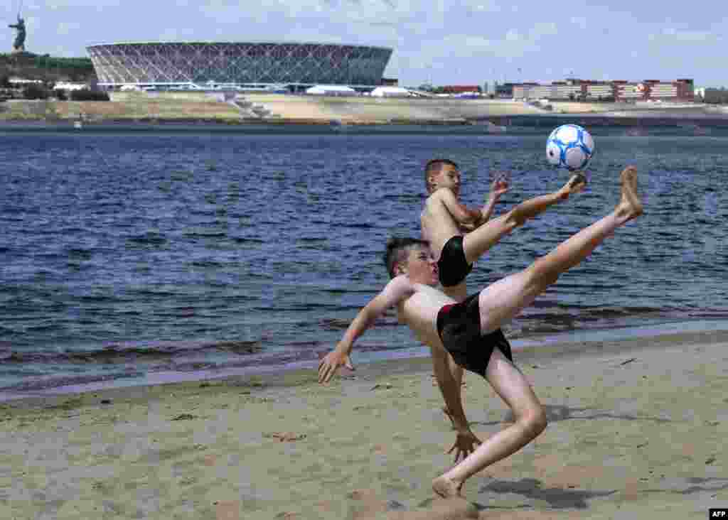 Children play football on a bank of the Volga river in front of the Volgograd arena, a venue of the 2018 World Cup in Russia.