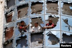 Workers clear broken glass from windows at a group of companies belonging to business tycoon Tawfeek Abdo Al-Raheem, which was damaged by fighting between Shi'ite Houthi rebels and government forces, in Sana'a, Sept. 28, 2014.