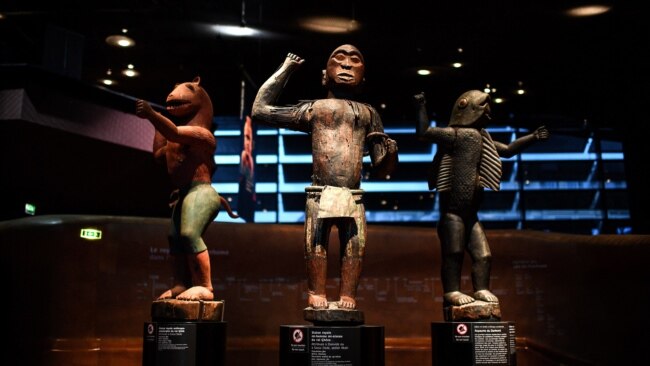 FILE - A visitor looks at statues of the 'Royal treasures of Abomey kingdom' on display at the Musee du quai Branly in Paris on Sept. 10, 2021, part of 26 artworks set to be restituted to Benin later in the year.