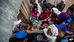 FILE - Displaced Tigrayans line up to receive food donated by local residents at a reception center for the internally displaced in Mekele, in the Tigray region of northern Ethiopia, May 9, 2021.