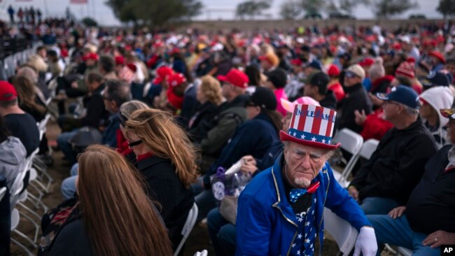 A supporter dressed as Uncle Sam listens to speakers prior to an appearance by former President Donald Trump at a rally on Jan. 15, 2022, in Florence, Ariz.