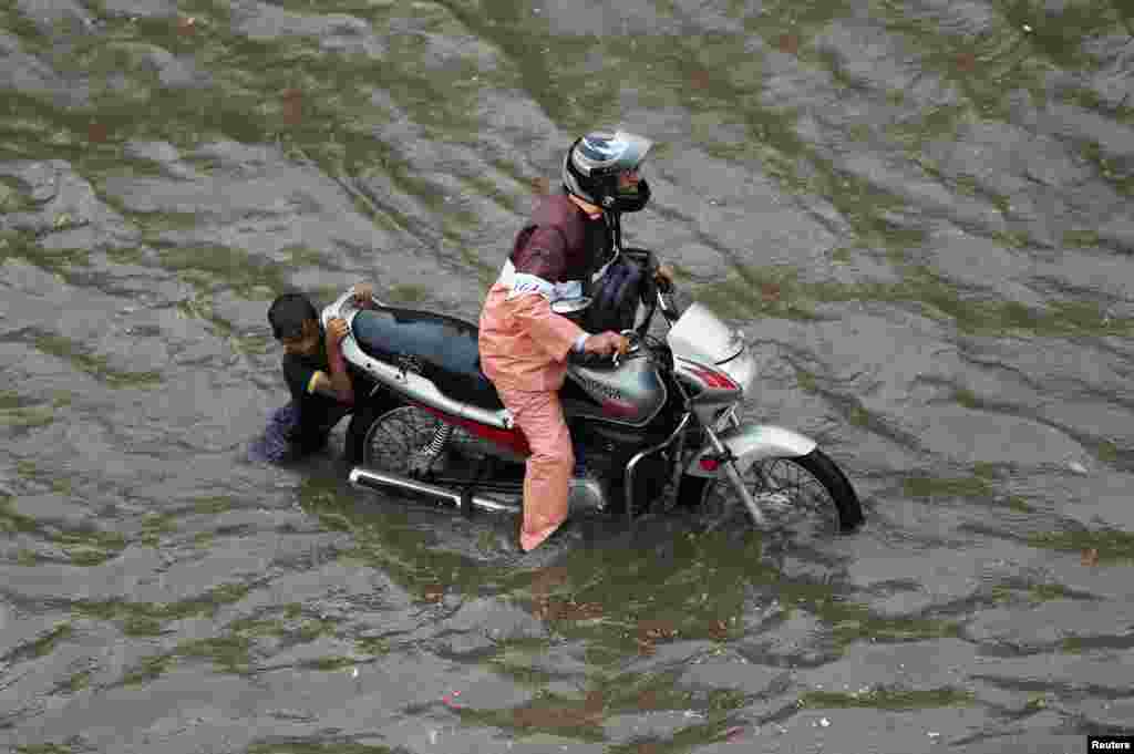 A man drags his motorcycle through a flooded road after a heavy rainfall in Ahmedabad, India.