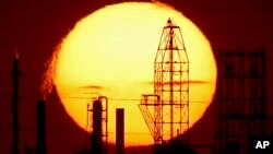 The National Cooperative Refinery Association oil refinery is silhouetted against the setting sun, Aug. 19, 2015, in McPherson, Kansas. 