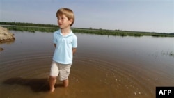 Cậu bé đứng nhìn vườn bắp của cha bị ngập nước
