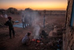 Warga Tigray yang melarikan diri dari wilayah Tigray di Etiopia menyiapkan api unggun untuk memasak makan malam di tempat pengungsian semetara di kamp Rakouba, di Qadarif, timur Sudan, 7 Desember 2020 (Foto: AP)