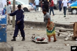 FILE - A woman looks at the body of a man killed during election protests in Kinshasa, Democratic Republic of Congo, Sept. 19, 2016.