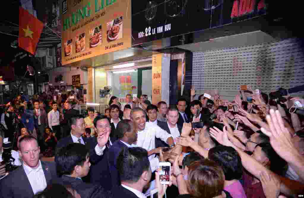 Presiden AS Barack Obama berjabat tangan dengan warga lokal saat meninggalkan sebuah restoran tempat ia makan malam dengan koki dan pembawa acara televisi Anthony Bourdain di Hanoi, Vietnam (23/5).&nbsp;