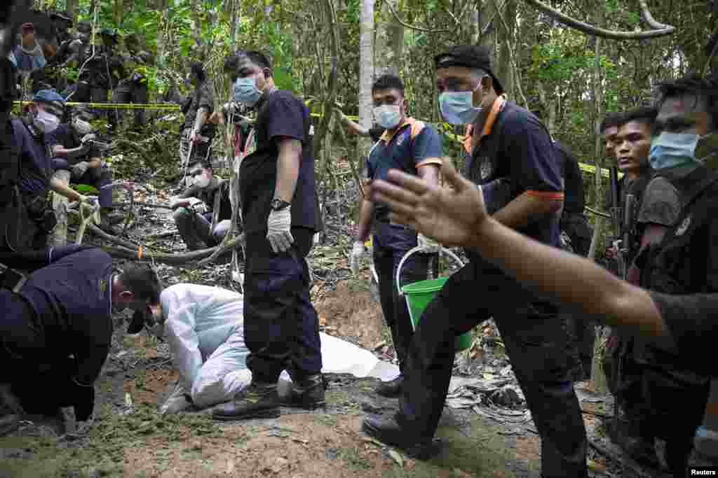 Tim forensik polisi menggali kuburan dekat kamp perdagangan manusia yang ditelantarkan di hutan dekat perbatasan Thailand di Bukit Wang Burma, Malaysia utara (27/5). ​(Reuters/Damir Sagolj)