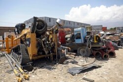 FILE - In this May 3, 2021 file photo, a man rests in the shade of destroyed machinery sold by the US military to a scrapyard, outside Bagram Air Base, in Afghanistan. (AP Photo/Rahmat Gul, File)