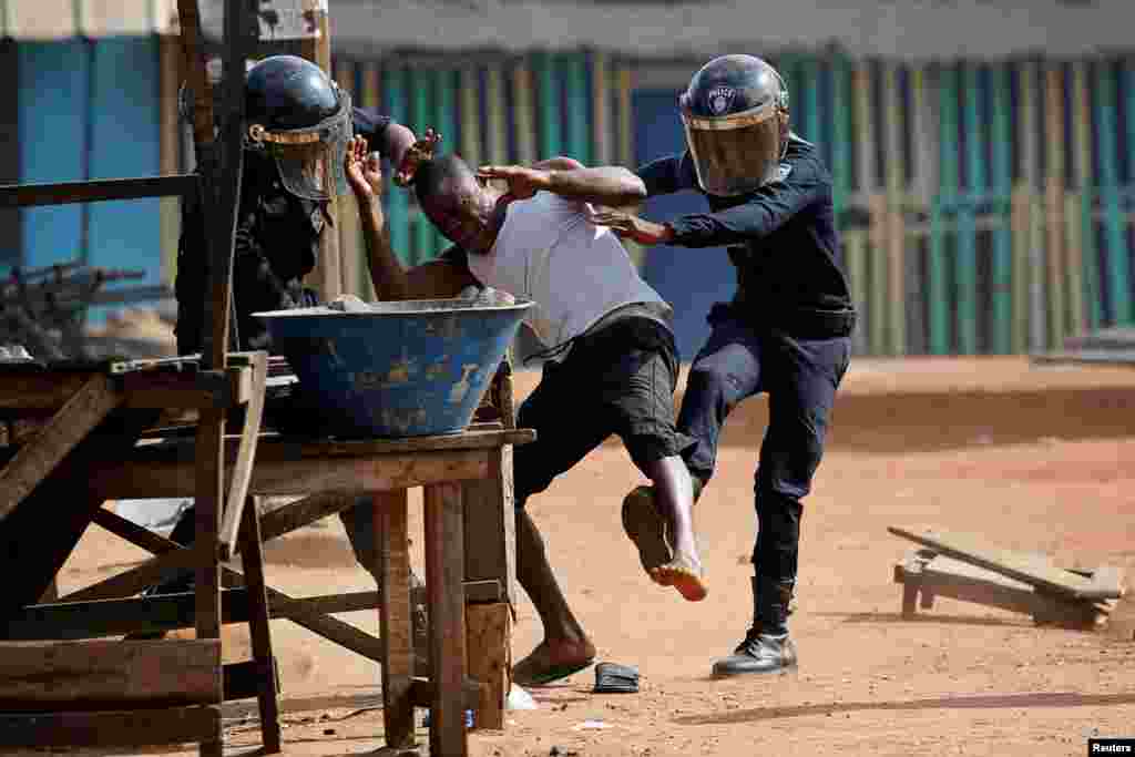 Policemen detain a demonstrator during a protest against President Alassane Ouattara&#39;s decision to stand for a third term, in Abidjan, Ivory Coast.