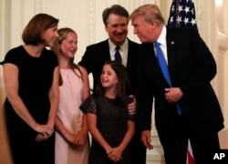 FILE - President Donald Trump talks with Judge Brett Kavanaugh, his Supreme Court nominee, and his family in the East Room of the White House, July 9, 2018.