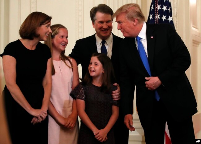 FILE - President Donald Trump talks with Judge Brett Kavanaugh and his family in the East Room of the White House, July 9, 2018.