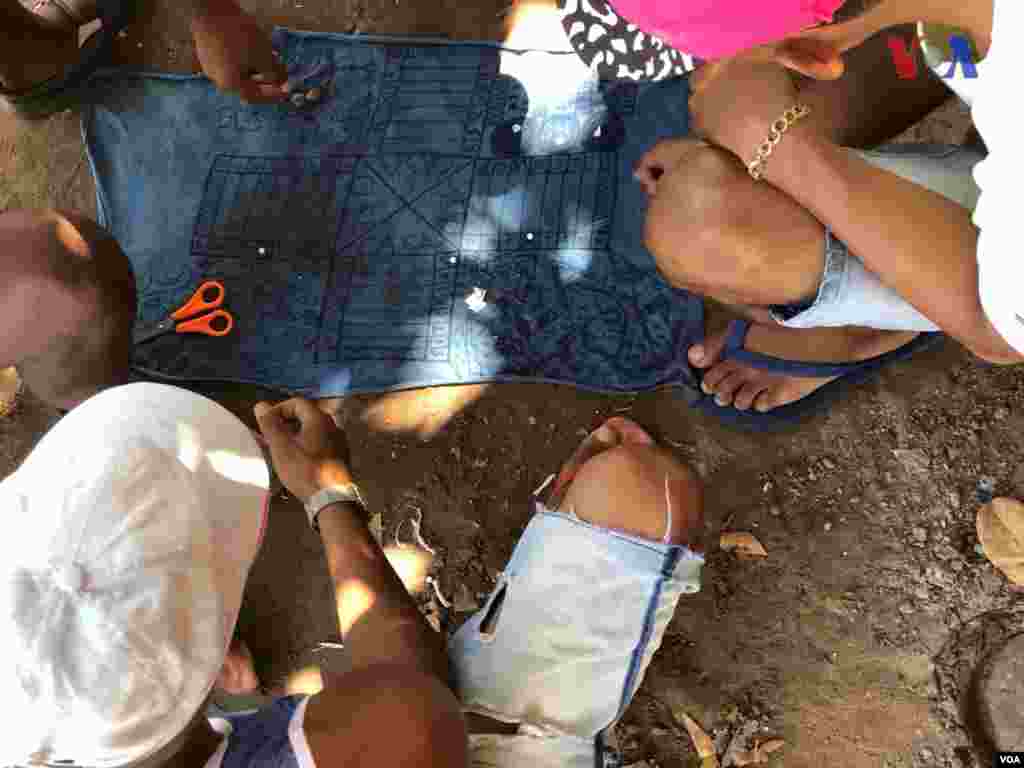 Personas juegan con un tablero hechos por ellos en refugio improvisado creado por venezolanos en el vecindario Jardim Floresta, fronterizo de Brasil. Foto: Celia Mendoza - VOA