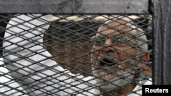Pemimpin Ikhwanul Muslimin Mohammed Badie meneriakkan slogan dari dalam kurungan, saat berada di ruang pengadilan di Kairo, 11 Desember 2013 (Foto:dok). Mesir mulai menggelar sidang pengadilan massa terbesar sejak penumpasan demo bulan Agustus 2013 yang lalu, Sabtu (22/3) dengan mengadili Badie, pemimpin agung kelompok Ikhwanul Muslimin yang sekarang dinyatakan terlarang di Mesir.