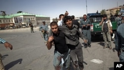 An Afghan policeman helps a wounded man away from the site of an attack at a Kabul police station, June 18, 2011