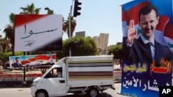 A vehicle drives past campaign posters of the June 3 presidential election in Damascus, Syria, May 12, 2014. 