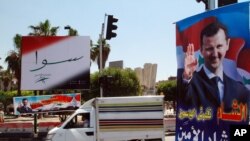 5月12日一辆卡车驶过大马士革大街上悬挂的总统大选宣传画