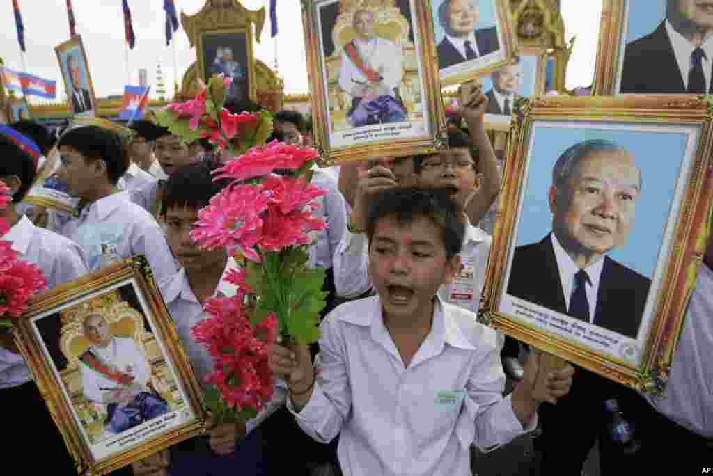 Cambodian students hold portraits of former King Norodom Sihanouk, right, King Norodom Sihamoni, and flowers during an Independence Day celebration at the Independence Monument in Phnom Penh, Cambodia, Wednesday, Nov. 9, 2011.