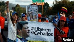 FILE - Patricia de Ceballos, left, wife of jailed former Mayor Daniel Ceballos, stands next to a banner reading "Release Ceballos" while campaigning to become mayor herself in San Cristobal, Venezuela, May 23, 2014.