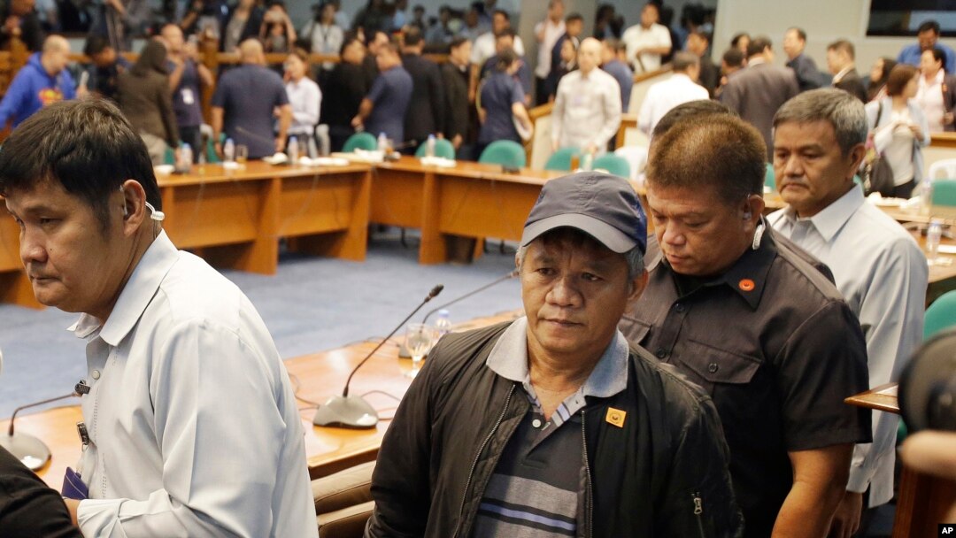 Mantan anggota milisi Filipina Edgar Matobato (tengah) dikawal secara ketat setelah bersaksi di Senat, di Pasay, bagian selatan Manila (15/9). (AP/Aaron Favila)