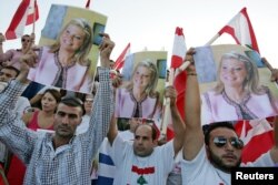FILE - Lebanese protesters carry posters of prominent anti-Syrian news anchor May Chidiac, who was seriously wounded by a car bomb, during a sit-in at Martyrs square in Beirut, Sept. 26, 2005.