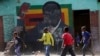 Children play soccer next to a defaced portrait of former Zimbabwean President Robert Mugabe in Harare, Sept, 6 2019.