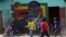 Children play soccer next to a defaced portrait of former Zimbabwean President Robert Mugabe in Harare, Sept, 6 2019.