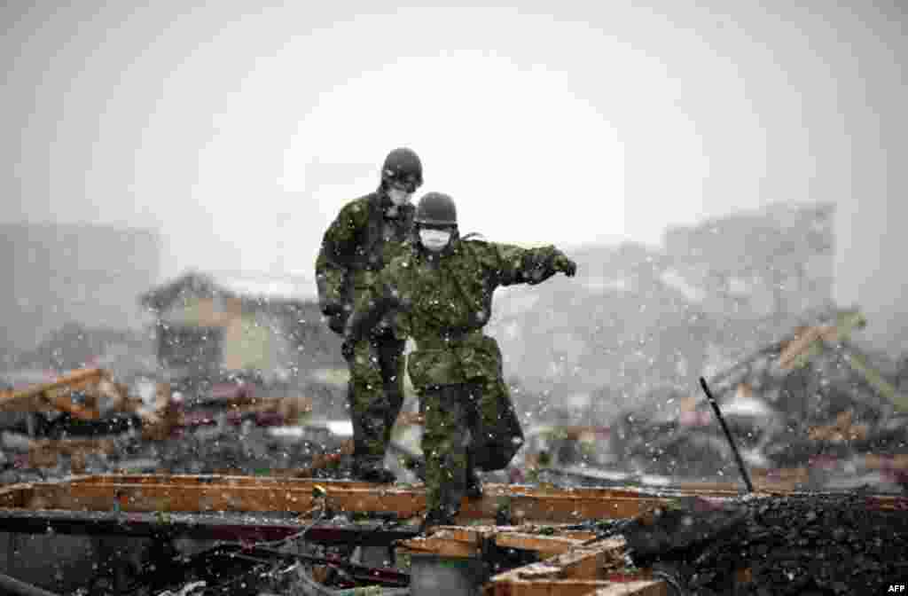 Members of the Japan Self-Defense Force make their way through the ruins of the devastated residential area in Otsuchi as heavy snow falls March 16, 2011. In the fishermen town of Otsuchi in Iwate prefecture, 12,000 out of a population of 15,000 have disa