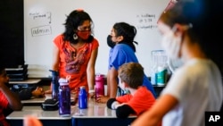 Student teacher Olivia Vazquez, standing, left, speaks with a student at the Eliza B. Kirkbride School in Philadelphia, Wednesday, Oct. 20, 2021. (AP Photo/Matt Rourke)