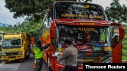 Policías inspeccionan un autobús en el primer día de una prohibición de viajes en Indonesia para las celebraciones de Eid al-Fitr en un esfuerzo por contener la pandemia del coronavirus, en Tasikmalaya, provincia de Java Occidental, el 6 de mayo de 2021.