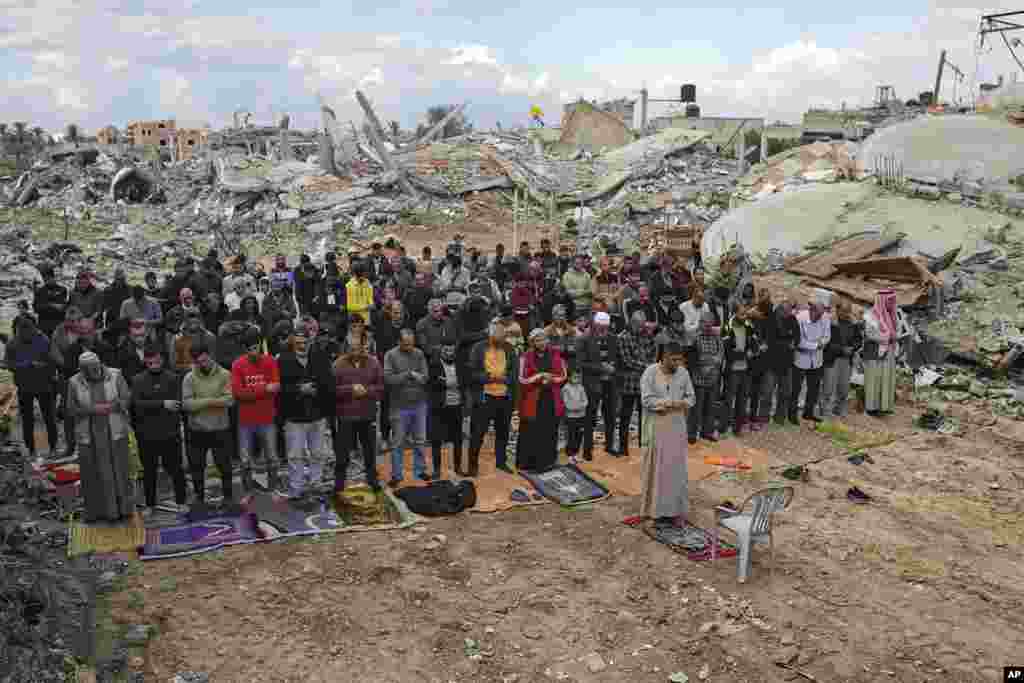 Palestinians perform Friday prayers near the ruins of a mosque destroyed by Israeli airstrikes in Khan Younis, Gaza Strip.