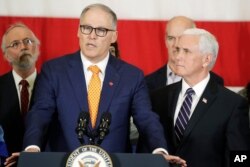 Vice President Mike Pence, right, looks on as Gov. Jay Inslee speaks during a news conference, March 5, 2020, at Camp Murray in Washington state. Pence was in the state to discuss its efforts to fight the spread of the coronavirus.