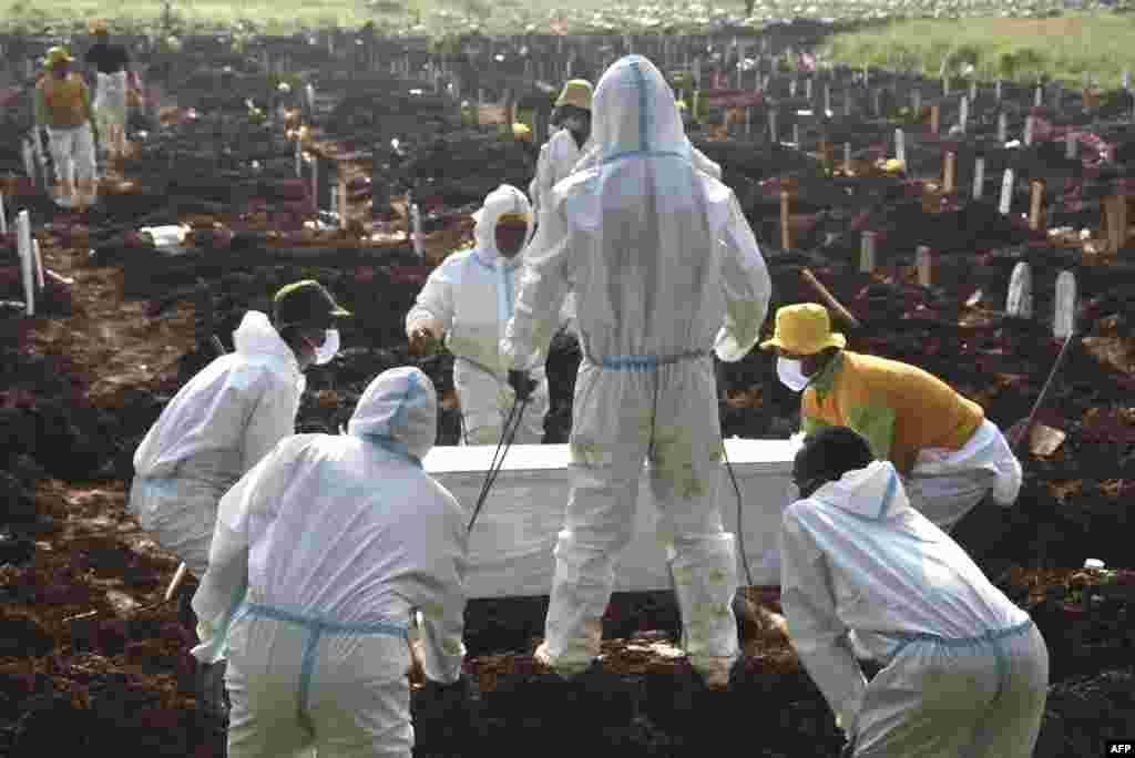 Gravediggers bury a coffin of a Covid-19 coronavirus victim at a cemetary in Bekasi, Indonesia.