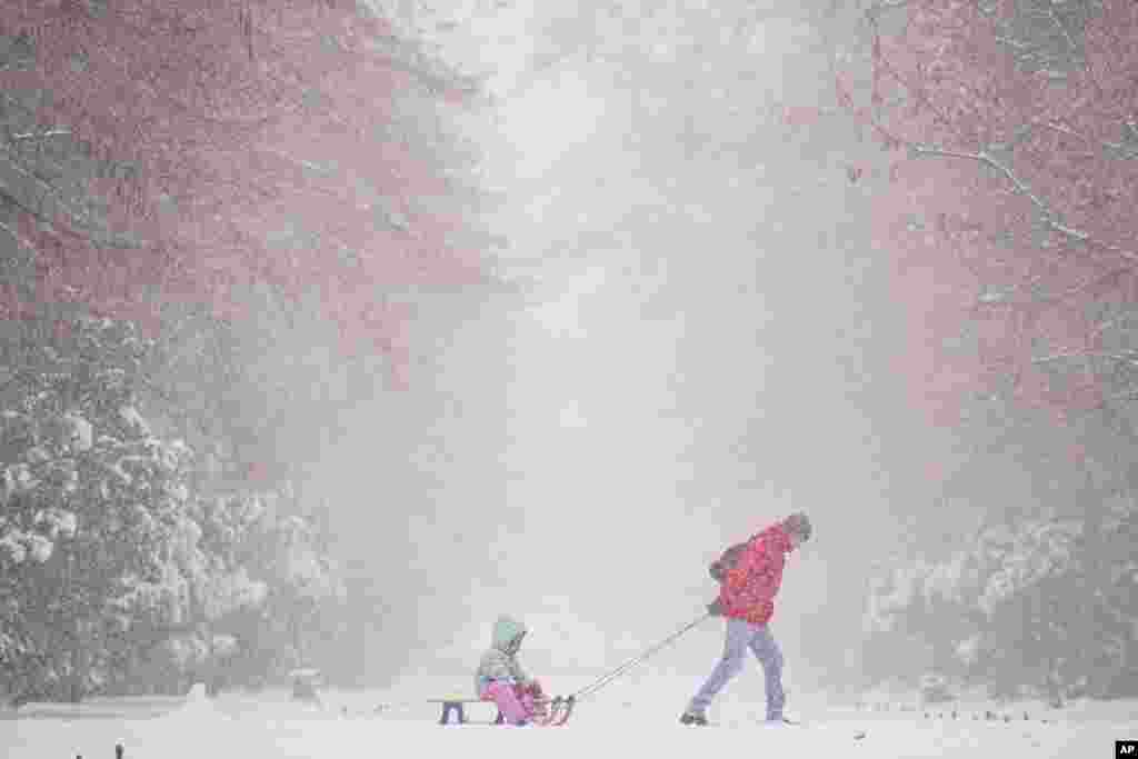 A man pulls a child on a sled during a snowfall in Bucharest, Romania.