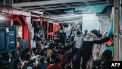This handout photo from SOS Mediterranee on July 6, 2021, shows some of the 369 migrants rescued from a large wooden boat in the Meditterranean Sea off the coast of Libya, as they gather on the deck of rescue vessel Ocean Viking.