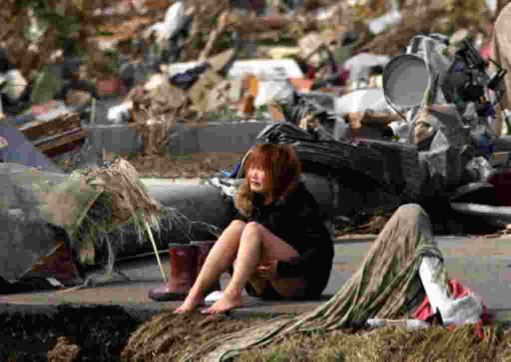 Una mujer llora, rodeada de los restos asolados entorno a una carretera destruida en la ciudad de Natori, en la prefectura de Miyagi.