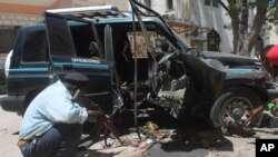 Polisi Somalia memeriksa rongsokan mobil setelah ledakan di Mogadishu hari Senin (21/4).