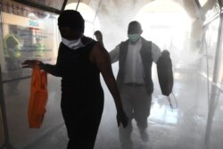 Passengers walk through a disinfectant tunnel before boarding the commuter train at the main railway station as a measure to contain the spread of the COVID-19, in Nairobi, Kenya, May 4, 2020.