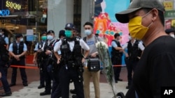 A man holds flowers to mourn the death of the assailant who stabbed a police officer in Hong Kong, July 2, 2021. 