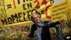 A woman holds a board that reads in French: 'One billion for Notre Dame! Zero for homeless' next to a banner that read also in French: 'One billion in 24 hours! Homeless Zero' during a protest in front of the Notre Dame cathedral in Paris, April 22, 2019.